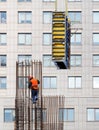 A builder wearing a bright orange waistcoat and a safety helmet installs the formwork on a steel frame for the subsequent pouring Royalty Free Stock Photo