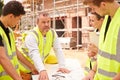 Builder On Building Site Discussing Work With Apprentice Royalty Free Stock Photo