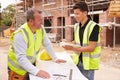 Builder On Building Site Discussing Work With Apprentice