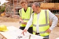 Builder On Building Site Discussing Work With Apprentice Royalty Free Stock Photo