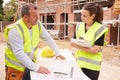 Builder On Building Site Discussing Work With Apprentice Royalty Free Stock Photo