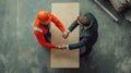 A Builder and a Businessperson Shake Hands on A Table Showing Partnership Concept Royalty Free Stock Photo