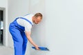 The builder carefully corrects the irregularities of the wall with a trowel. Builder in work clothes against a gray wall. Photo