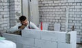 Builder checking evenness of aerated concrete wall with spirit level Royalty Free Stock Photo