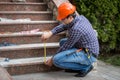 Builder checking stairs height by measuring tape
