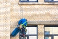 Builder climber hanging on safety ropes on the wall of an old building with a set of different tools behind Royalty Free Stock Photo