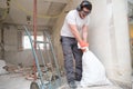 Builder collecting construction debris in a bag, and carrying in a hand trolley