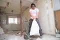 Builder collecting construction debris in a bag, and carrying in a hand trolley Royalty Free Stock Photo