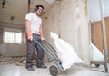 Builder collecting construction debris in a bag, and carrying in a hand trolley Royalty Free Stock Photo