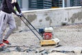The builder compacts crushed stone with a gasoline vibratory compactor for subsequent laying of paving slabs Royalty Free Stock Photo