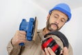 Builder considering wearing earmuffs while using sander Royalty Free Stock Photo