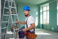 Builder contractor bearded man in helmet smiling while standing at a construction site.