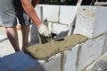 Builder contractor laying white autoclaved aerated concrete AAC blocks with concrete during house blocks wall construction