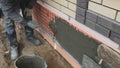 Builder faces the basement of a house with a wild stone. Flat for cladding, tabata on the construction site.