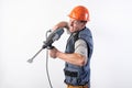 A builder with a funny expression, in a helmet, with a drill-puncher