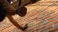 builder with a grinder and a stone cutting disc stands by a brick wall Royalty Free Stock Photo