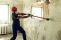 Builder with a hammer in his hands breaks the cement wall The builder is dressed in a protective suit and helmet Royalty Free Stock Photo