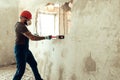 Builder with a hammer in his hands breaks the cement wall The builder is dressed in a protective suit and helmet Royalty Free Stock Photo