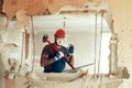 Builder with a hammer in his hands breaks the cement wall The builder is dressed in a protective suit and helmet Royalty Free Stock Photo