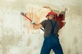 Builder with a hammer in his hands breaks the cement wall The builder is dressed in a protective suit and helmet Royalty Free Stock Photo