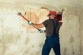 Builder with a hammer in his hands breaks the cement wall The builder is dressed in a protective suit and helmet Royalty Free Stock Photo