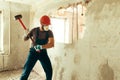 Builder with a hammer in his hands breaks the cement wall The builder is dressed in a protective suit and helmet Royalty Free Stock Photo