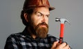 Builder in hard hat with hammer. Portrait of bearded workman in hardhat. Building. Repairment.