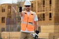 Builder in a hard hat working on a construction project at a site. Worker hold phone, builder show phone screen Royalty Free Stock Photo