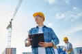 Builder in hardhat with clipboard at construction Royalty Free Stock Photo