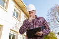 Builder in hardhat with clipboard and pencil outdoors Royalty Free Stock Photo