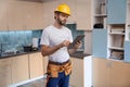 Builder in helmet working with tablet on kitchen background Royalty Free Stock Photo