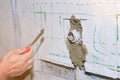 Builder holds a spatula in his hand and covered with cement mortar hole with pipe in the wall