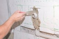 Builder holds a spatula in his hand and covered with cement mortar hole with pipe in the wall Royalty Free Stock Photo