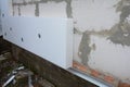 Builder installing anchors in house wall for rigid insulation foam