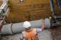 Builder installing big diameter concrete drainage pipe protected by trench support system during deep drainage works Royalty Free Stock Photo