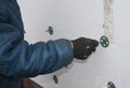 Builder installing foam insulation board with plastic nails and hammer for house energy saving. House foam insulation outdoors