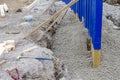 Builder installing rail slippers painted blue into semi-dry concrete to form a secure barrier around new school playground as part
