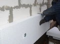 Builder installing rigid styrofoam insulation board on house wall