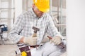 Builder kneeling using a chisel and mallet