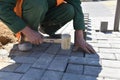 A builder knocks a hammer on a concrete gray tile.