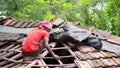 Builder labour worker repairing soiled tiles rooftop of a house in West Bengal, India on July 2020