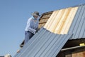 Builder lifts, holds roofing iron to repair the roof