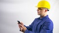 A builder looks at the phone,reads a message,a worker in a yellow helmet on his head,construction worker.On a white background.