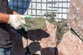 Builder - mason hands placing stones on a wall using a spatula with cement, outdoors