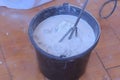 Builder mixing cement plaster in bucket using an electric mixer, closeup view.