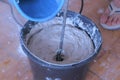 Builder mixing cement plaster in bucket using an electric mixer, closeup view. Royalty Free Stock Photo