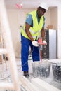 Builder mixing plaster in bucket with electric mixer closeup