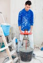 builder mixing plaster in bucket using electric mixer