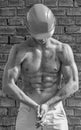 Builder with muscular torso and helmet, brick wall on background. builder concept. Athlete posing with nude