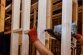 A builder nails wooden beams to house frameworks with use of an air hammer